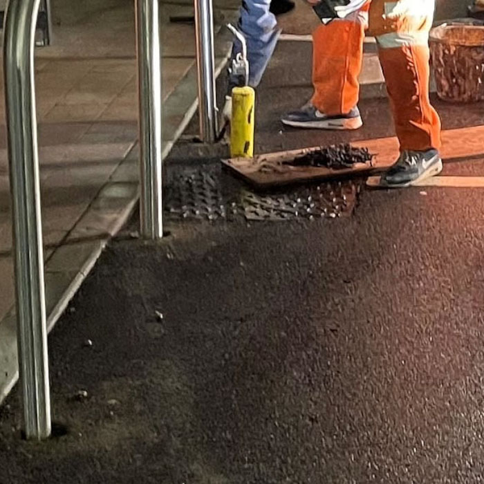 contractor in orange high vis installation bollard in a london car park